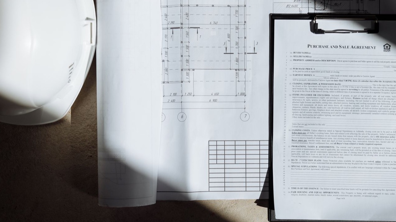 Top view of construction documents and hard hat in sunlight, capturing planning essence. (Pexels photo)